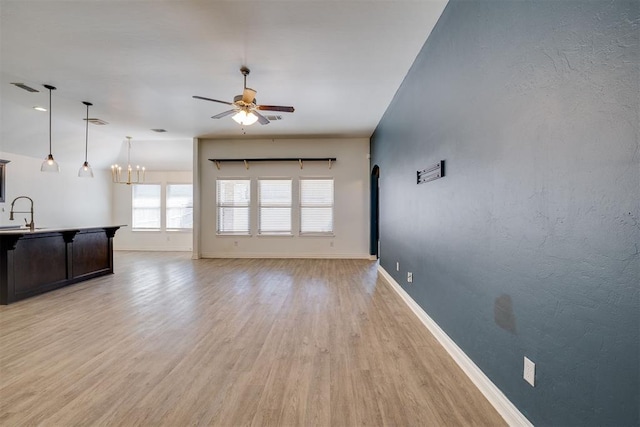 living area featuring arched walkways, a ceiling fan, light wood-type flooring, and baseboards