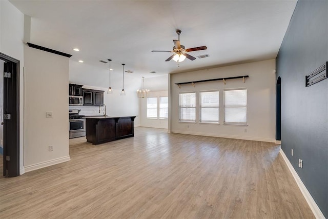 kitchen with visible vents, arched walkways, appliances with stainless steel finishes, ceiling fan with notable chandelier, and open floor plan