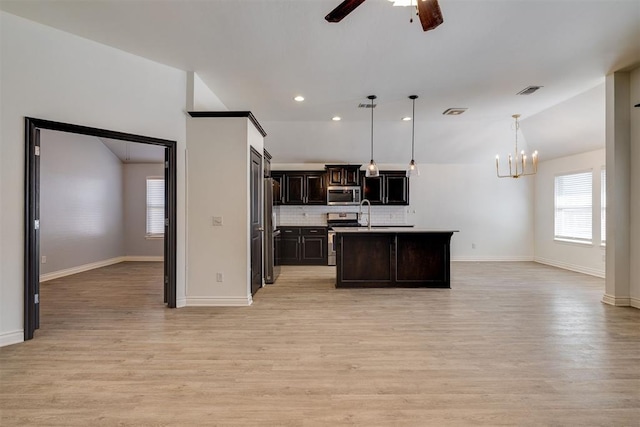 kitchen with backsplash, dark brown cabinetry, open floor plan, light wood-type flooring, and appliances with stainless steel finishes