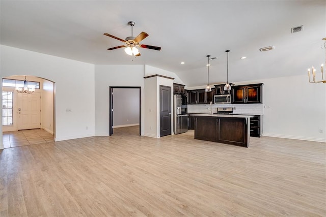 kitchen featuring visible vents, arched walkways, stainless steel appliances, open floor plan, and backsplash