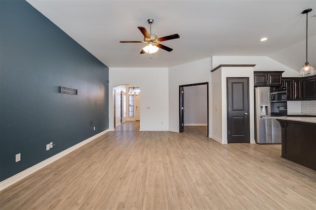 kitchen with a ceiling fan, decorative light fixtures, stainless steel appliances, arched walkways, and light wood-style floors