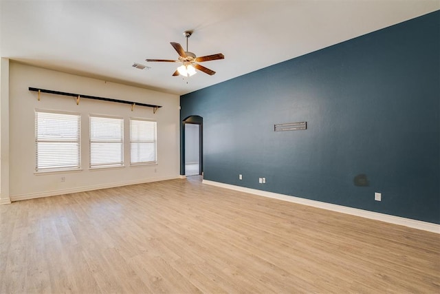 spare room featuring a ceiling fan, baseboards, visible vents, arched walkways, and light wood-type flooring