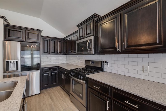 kitchen with tasteful backsplash, stainless steel appliances, dark brown cabinetry, light wood finished floors, and lofted ceiling