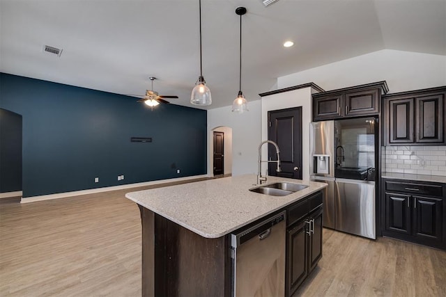 kitchen with visible vents, light wood-style flooring, arched walkways, a sink, and appliances with stainless steel finishes