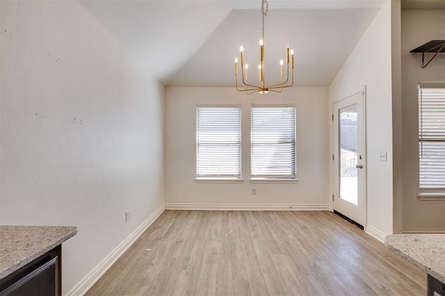 unfurnished dining area featuring a notable chandelier, light wood-style flooring, baseboards, and lofted ceiling