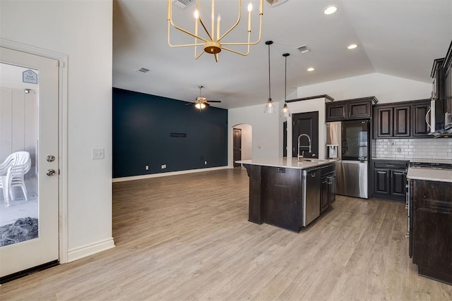 kitchen featuring tasteful backsplash, lofted ceiling, light wood-style flooring, arched walkways, and stainless steel appliances