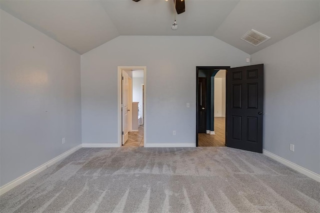 unfurnished bedroom featuring lofted ceiling, carpet, and visible vents