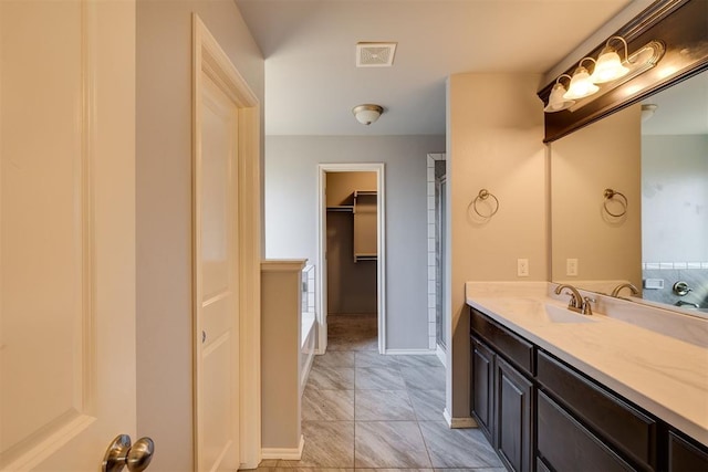 full bath with visible vents, a walk in closet, baseboards, a bathtub, and vanity