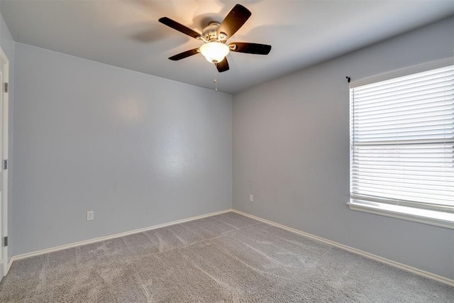 carpeted spare room featuring baseboards and ceiling fan