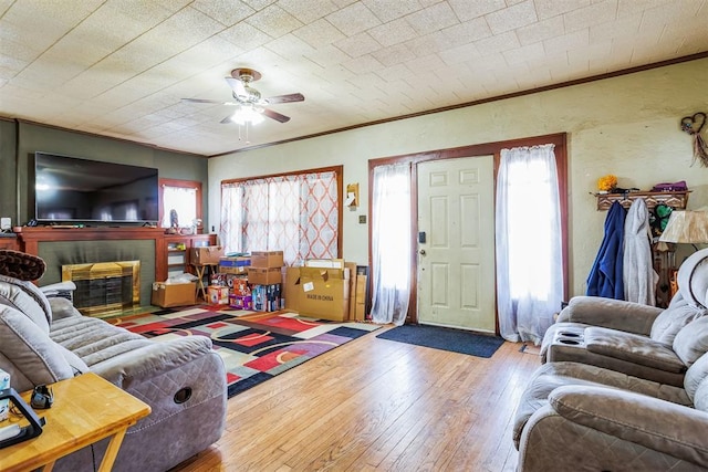 living area with hardwood / wood-style flooring, a fireplace with flush hearth, crown molding, and a healthy amount of sunlight