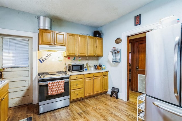 kitchen featuring visible vents, under cabinet range hood, light wood-style floors, appliances with stainless steel finishes, and light countertops