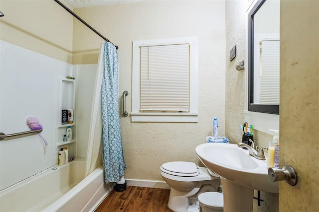 full bath featuring toilet, wood finished floors, shower / bath combination with curtain, baseboards, and a textured wall