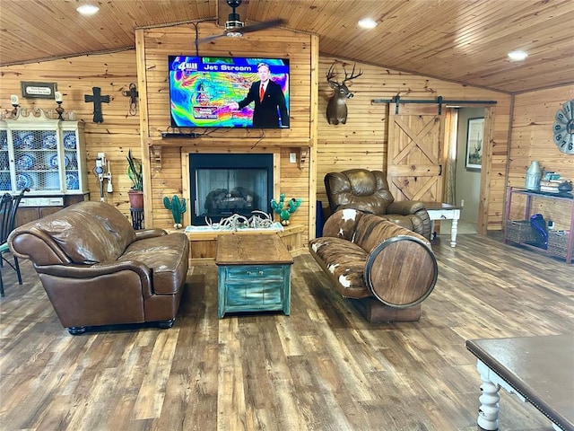 living room with a barn door, wooden ceiling, wood walls, and lofted ceiling