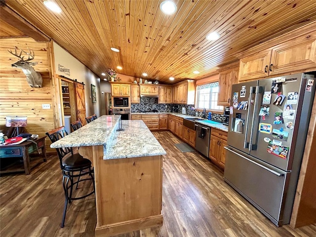 kitchen featuring a kitchen island, dark wood-type flooring, a kitchen bar, a barn door, and stainless steel appliances