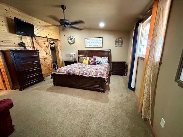 bedroom featuring wood walls, lofted ceiling, a barn door, light carpet, and a ceiling fan