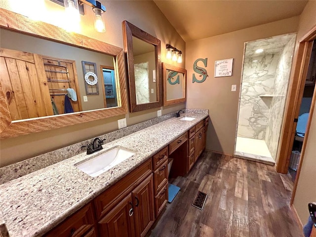 bathroom featuring vaulted ceiling, wood finished floors, double vanity, and a sink