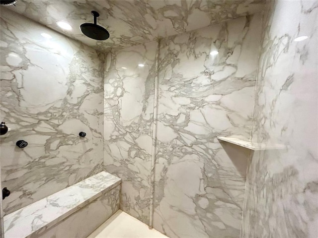 bathroom with stone wall and a marble finish shower