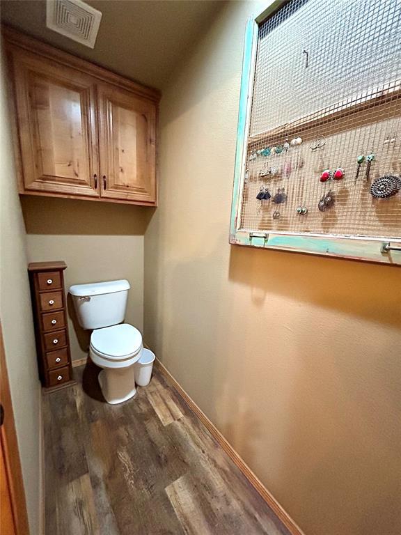 bathroom with visible vents, toilet, baseboards, and wood finished floors