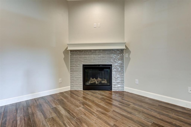 details featuring a glass covered fireplace, baseboards, and wood finished floors