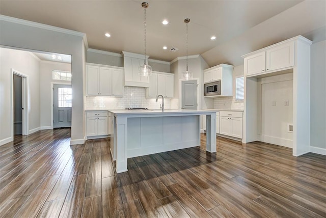 kitchen featuring stainless steel microwave, backsplash, white cabinets, and dark wood-style flooring