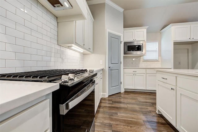 kitchen with stainless steel microwave, gas stove, dark wood-type flooring, and light countertops