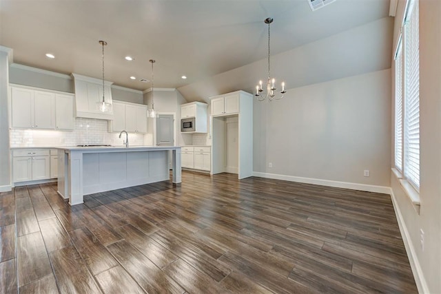 kitchen with dark wood finished floors, backsplash, white cabinetry, and an inviting chandelier