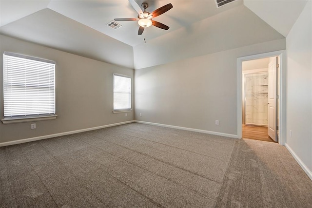 carpeted empty room with lofted ceiling, a ceiling fan, visible vents, and baseboards