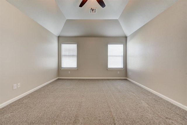 carpeted spare room with visible vents, baseboards, ceiling fan, and vaulted ceiling