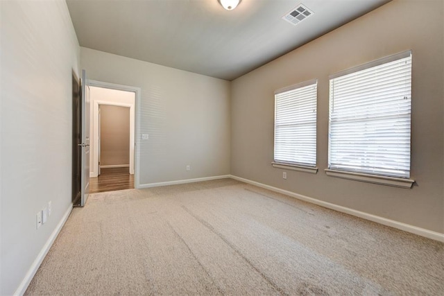 empty room with visible vents, carpet floors, and baseboards