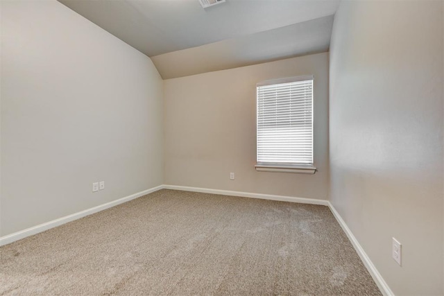 spare room featuring visible vents, baseboards, carpet, and vaulted ceiling