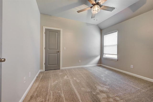 carpeted spare room with a ceiling fan, baseboards, and vaulted ceiling