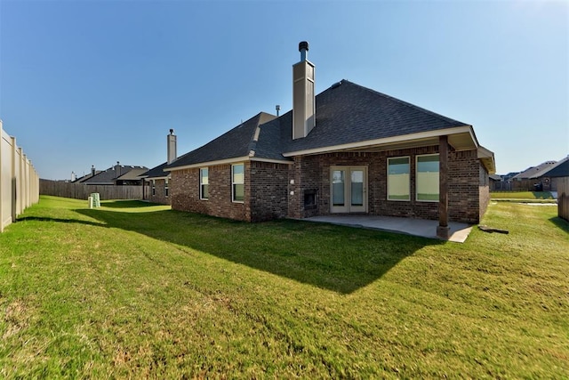 rear view of property with a yard, a fenced backyard, a chimney, a patio area, and brick siding