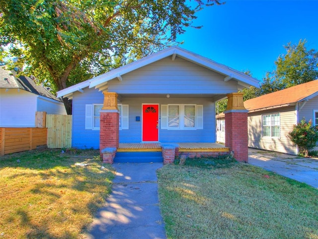 bungalow featuring a porch, a front lawn, and fence