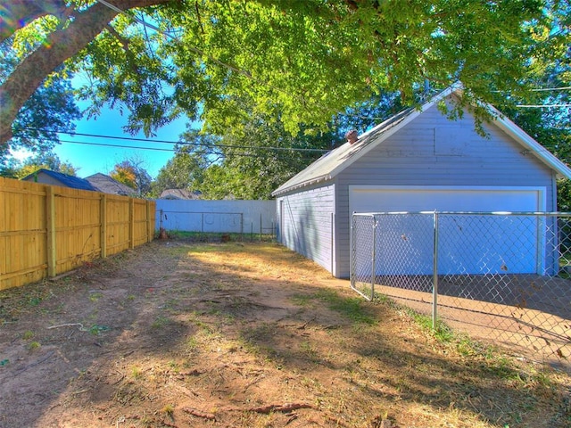 view of yard featuring a fenced backyard, a garage, and an outdoor structure