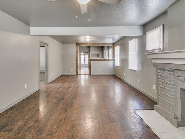 unfurnished living room featuring a fireplace, a ceiling fan, baseboards, and hardwood / wood-style flooring