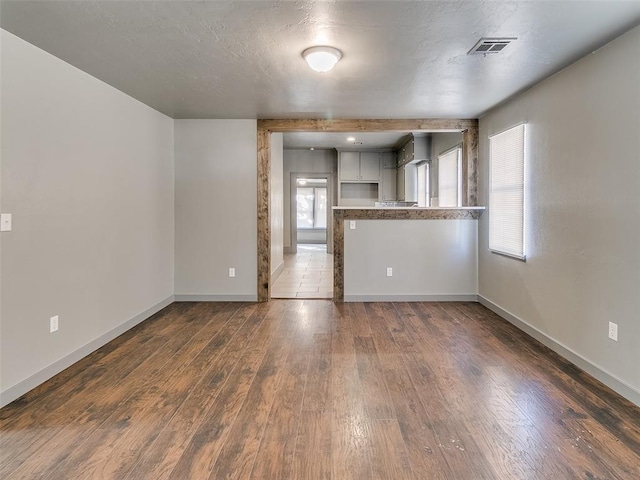 interior space featuring dark wood-style floors, visible vents, a textured ceiling, and baseboards