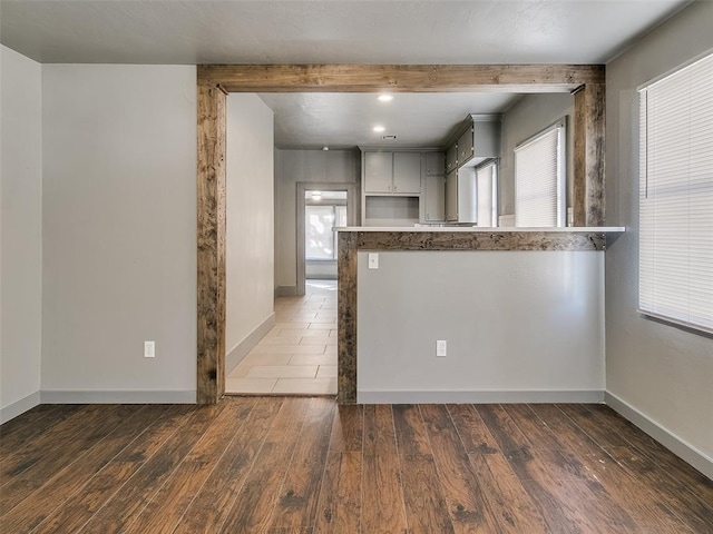 kitchen with wood finished floors, a healthy amount of sunlight, baseboards, and a peninsula