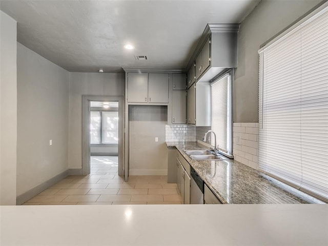 kitchen with baseboards, visible vents, a sink, dishwasher, and tasteful backsplash