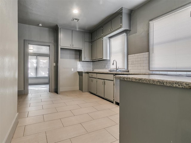 kitchen featuring decorative backsplash, visible vents, baseboards, and gray cabinets