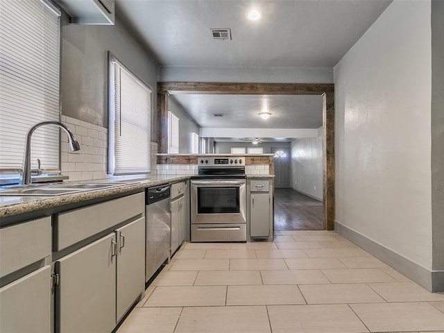 kitchen featuring visible vents, a sink, tasteful backsplash, appliances with stainless steel finishes, and a peninsula