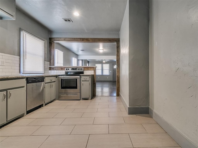 kitchen featuring baseboards, visible vents, stainless steel appliances, light countertops, and tasteful backsplash