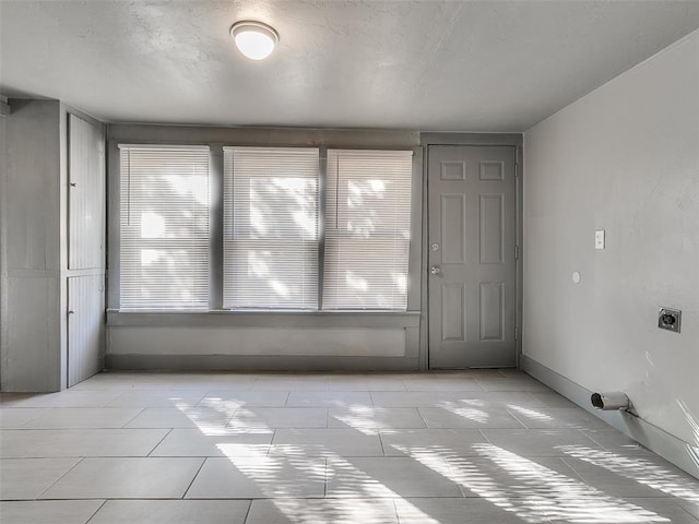 empty room featuring baseboards and light tile patterned flooring