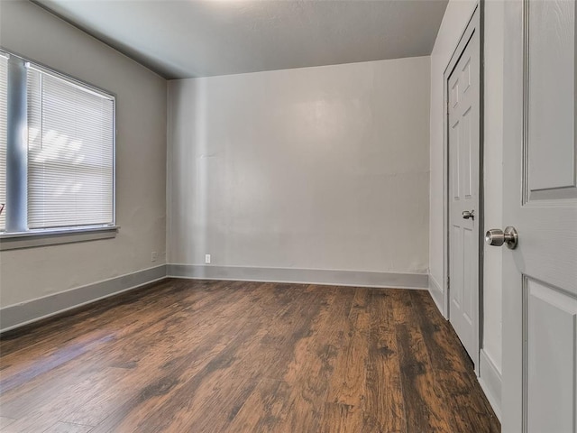 unfurnished room featuring baseboards and dark wood-style flooring