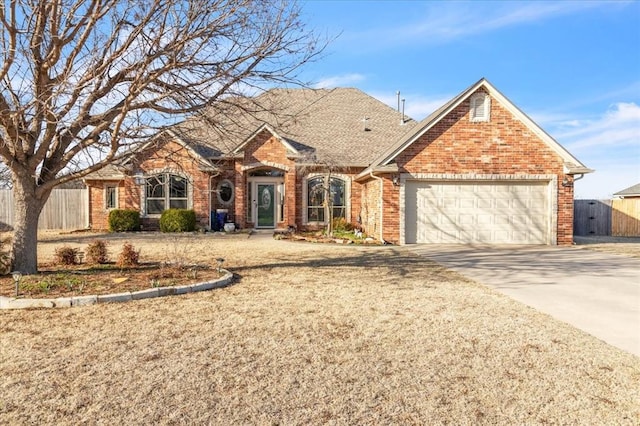 view of front of home with brick siding, fence, concrete driveway, roof with shingles, and a garage