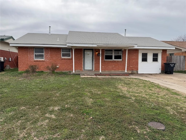 single story home featuring brick siding, roof with shingles, a front lawn, and fence