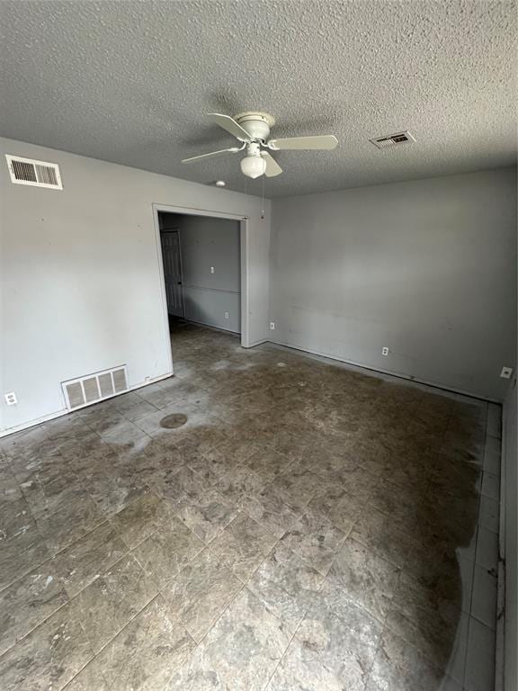 empty room featuring a textured ceiling, visible vents, and ceiling fan