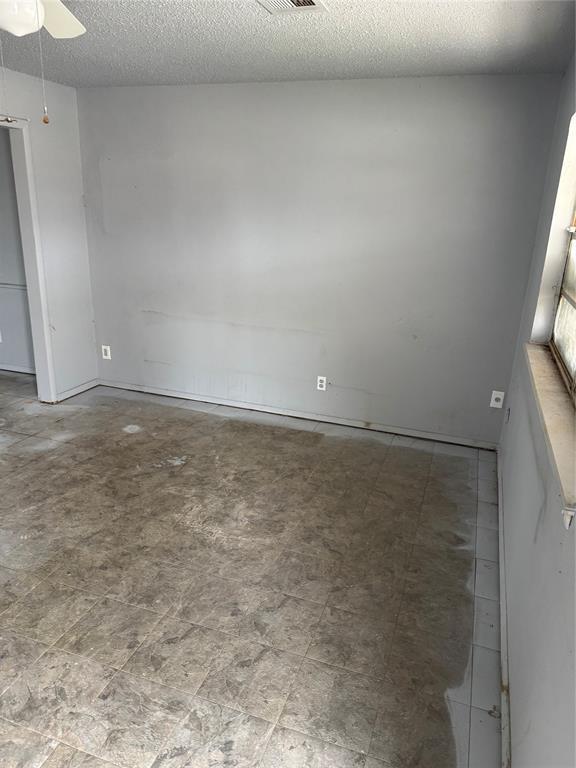 empty room with ceiling fan and a textured ceiling