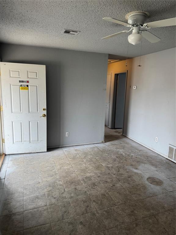 empty room with visible vents, a textured ceiling, and a ceiling fan