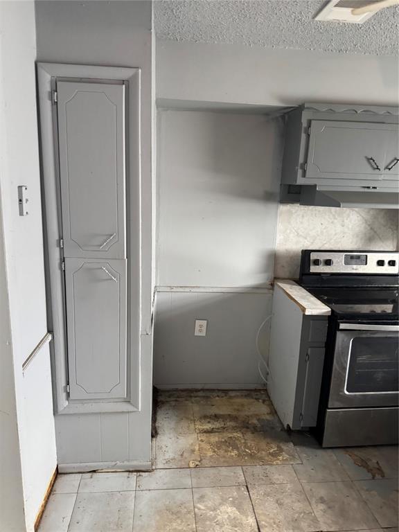 kitchen with stainless steel range with electric stovetop, gray cabinets, under cabinet range hood, and a textured ceiling