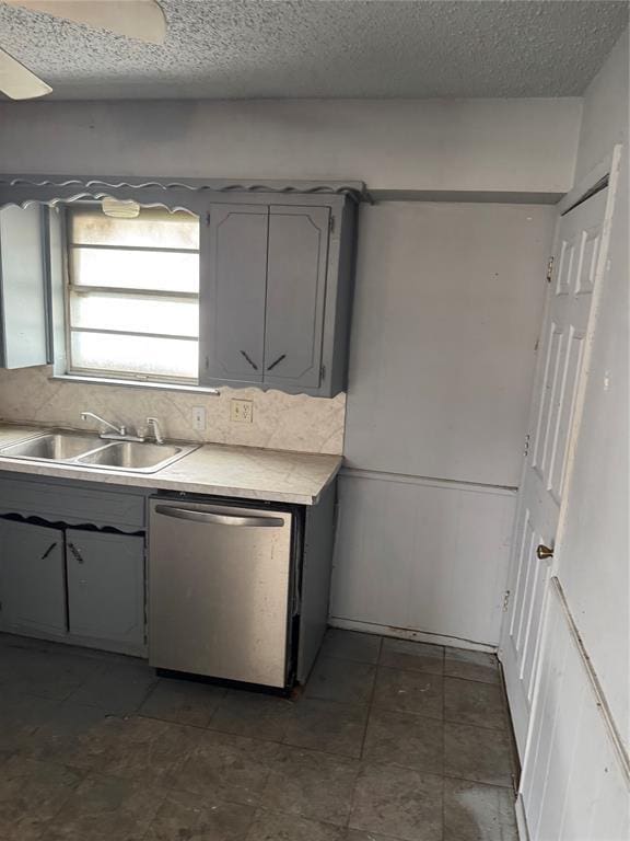 kitchen with gray cabinetry, dishwasher, light countertops, a textured ceiling, and a sink